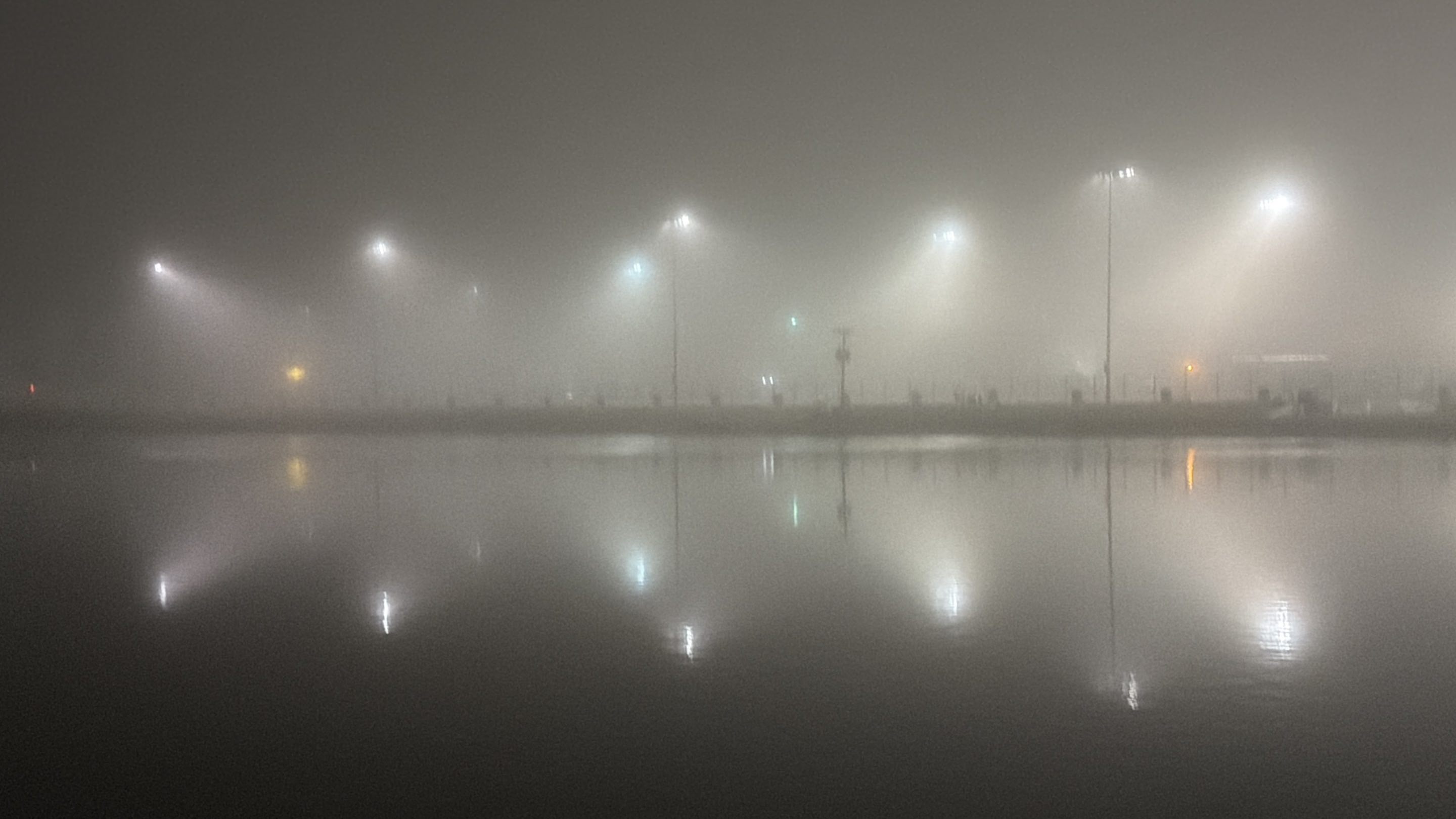 floodlights in dark fog reflected off the surface of a lake